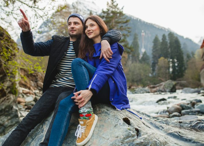 youngyoung hipster beautiful couple in love walking on a rocks at river in winter forest, jeans, warm coat, sneakers, smiling, having fun, traveling, hiking, vacation, love, romance hipster beautiful couple in love walking on a rocks at river in winter forest, jeans, warm coat, sneakers, smiling, having fun, traveling, hiking, vacation, love, romance